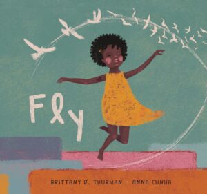 Book cover for Fly by Brittany J. Thurman. Image depict a young Black girl dancing with birds flying overhead