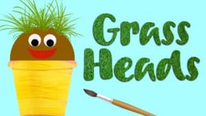 reads "Grass Heads" against a blue background. A pot with compost and grass growing out of the top is to the left of the title. The grass head pot has googly eyes and a felt mouth. A paintbrush is under the title.